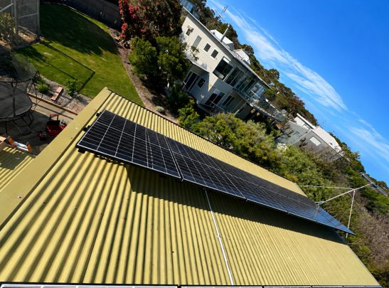 Solar array on the tin roof with a clear view of the ocean and a tennis court in the distance