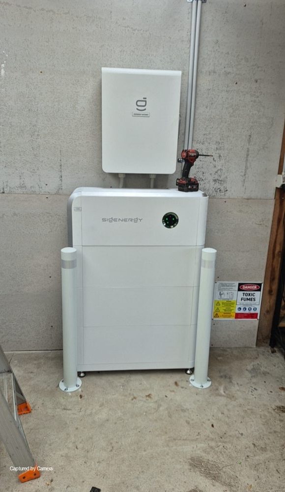 Sigenergy sigen hybrid inverter and sigenstor battery, bollard-protected, on the south wall of daniel's baxter home