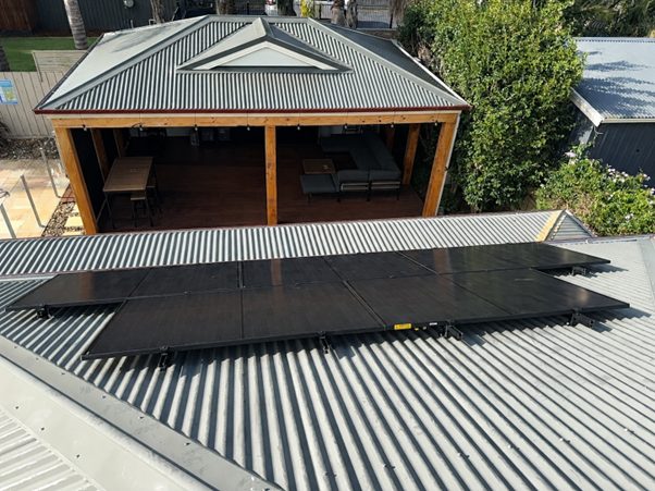 24 all-black aiko panels across the tin roof of rodney's beaconsfield home, alongside the outdoor entertaining area