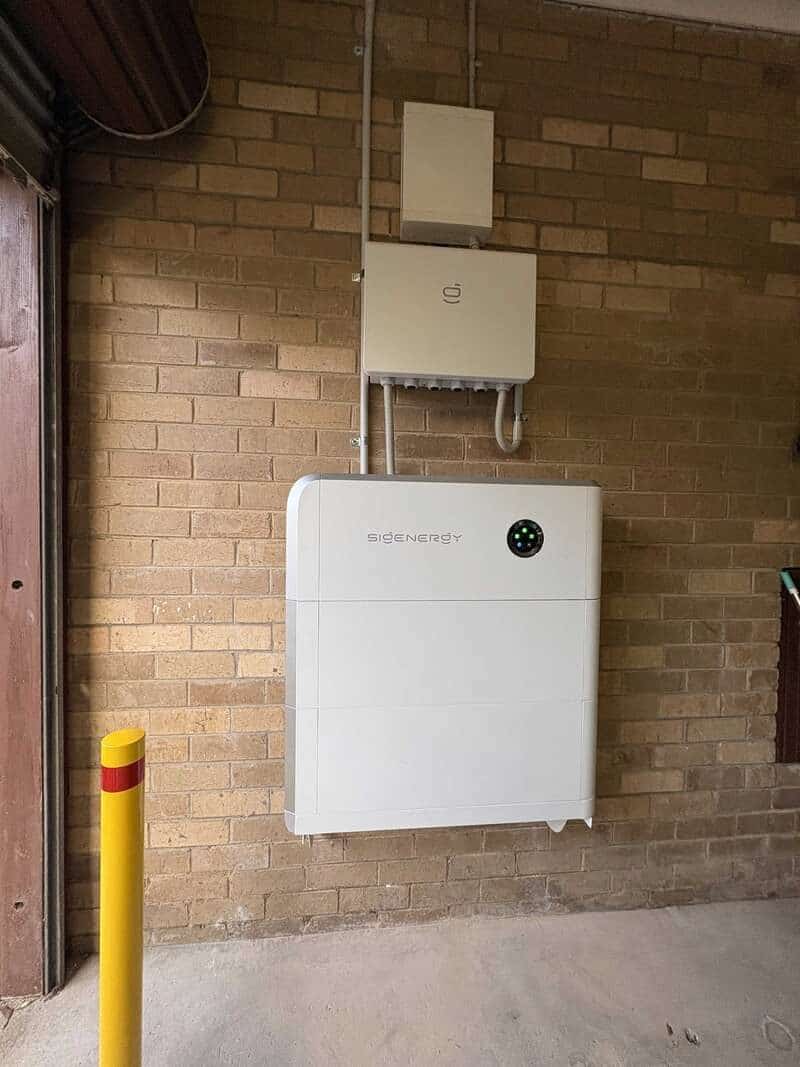 Sigenergy inverter and stacked battery modules mounted on the garage brick wall of a belgrave south home, bollard-protected