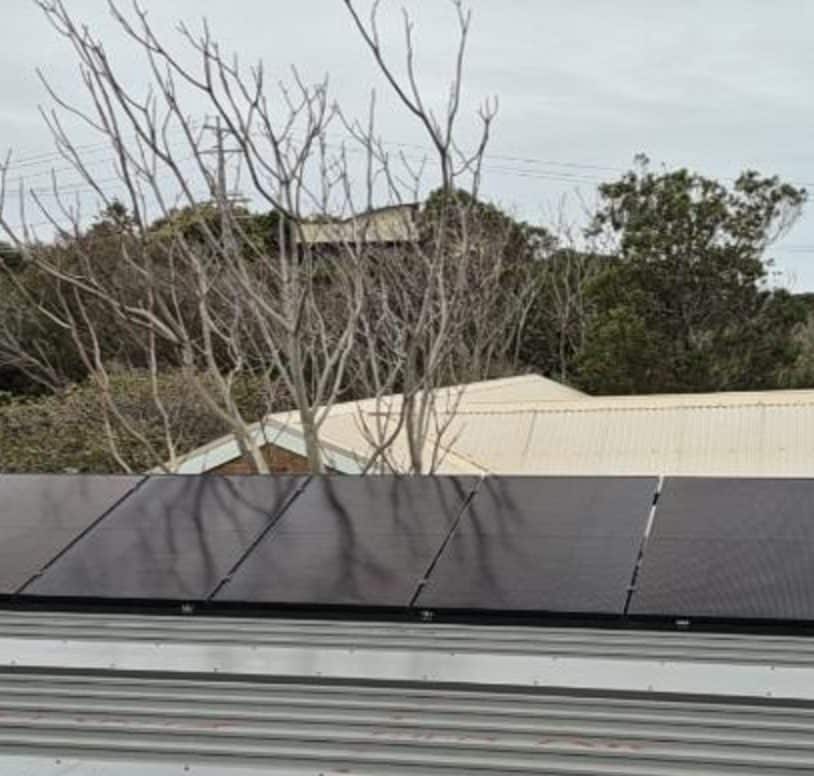 Twenty-seven jinko tiger neo iii panels raised on tilt frames above the klip-lok tin roof of a blairgowrie home, peninsula scrub behind