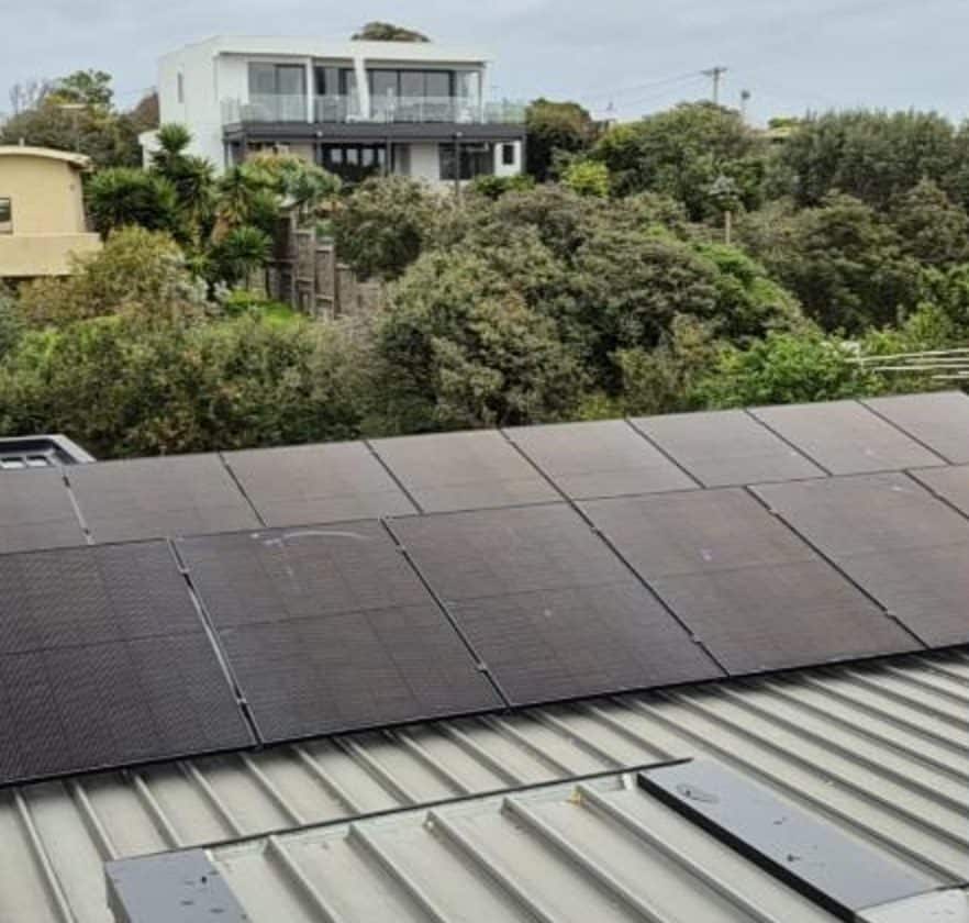The full 12. 825 kw jinko array across the tin roof of a single-storey blairgowrie home, looking out over the mornington peninsula