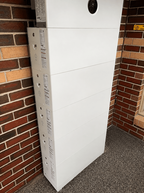 Five goodwe battery modules stacked against the brick wall of a beaconsfield home