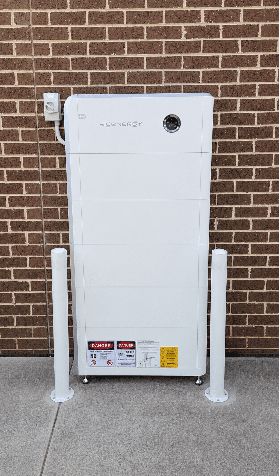 Five sigenergy sigenstor battery modules behind bollards against a brick wall in berwick