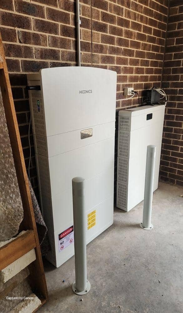 Inverter and battery storage units on a brick wall in the garage of a botanic ridge home