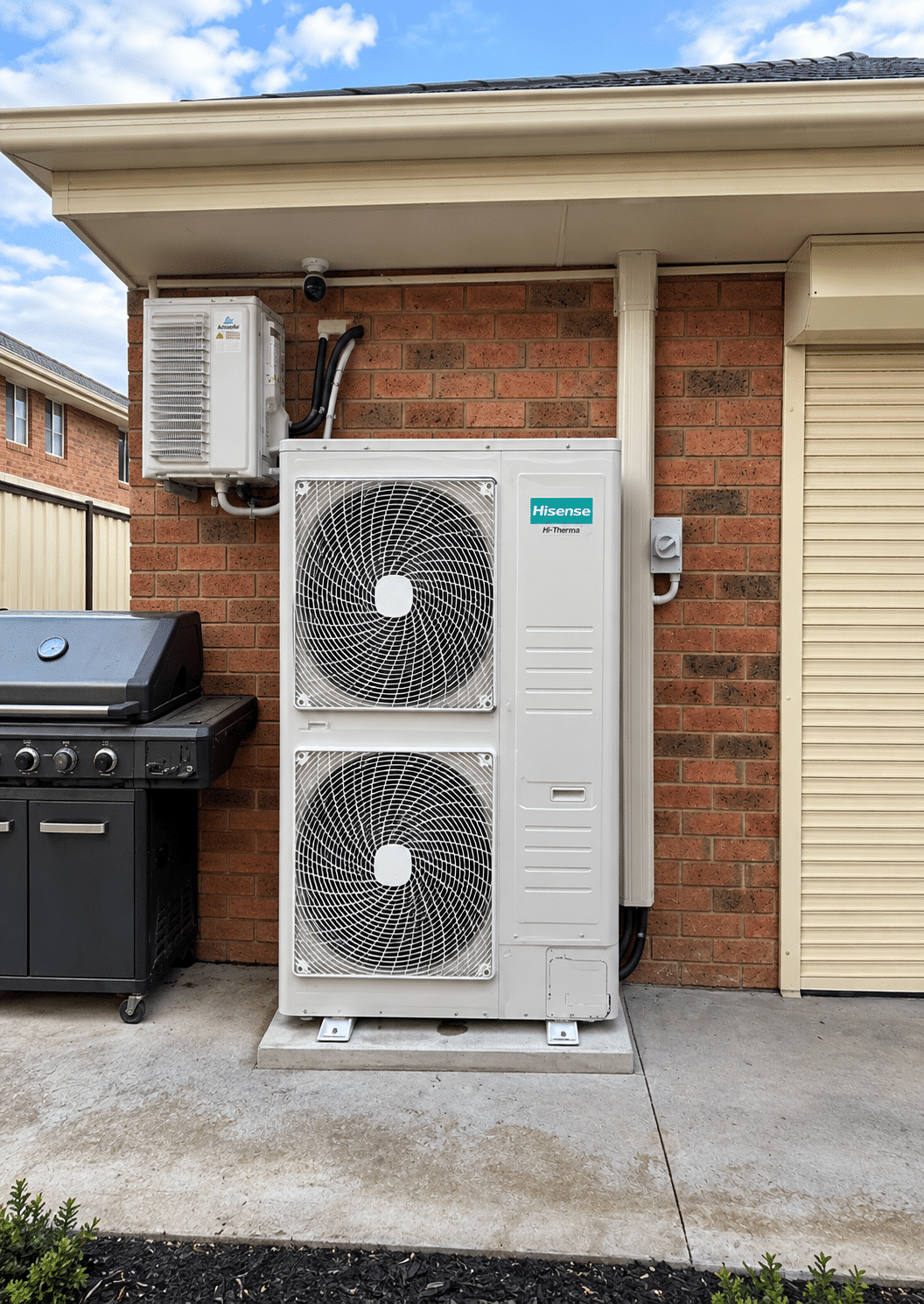 Ducted reverse cycle outdoor unit on a concrete pad against a brick wall in cairnlea
