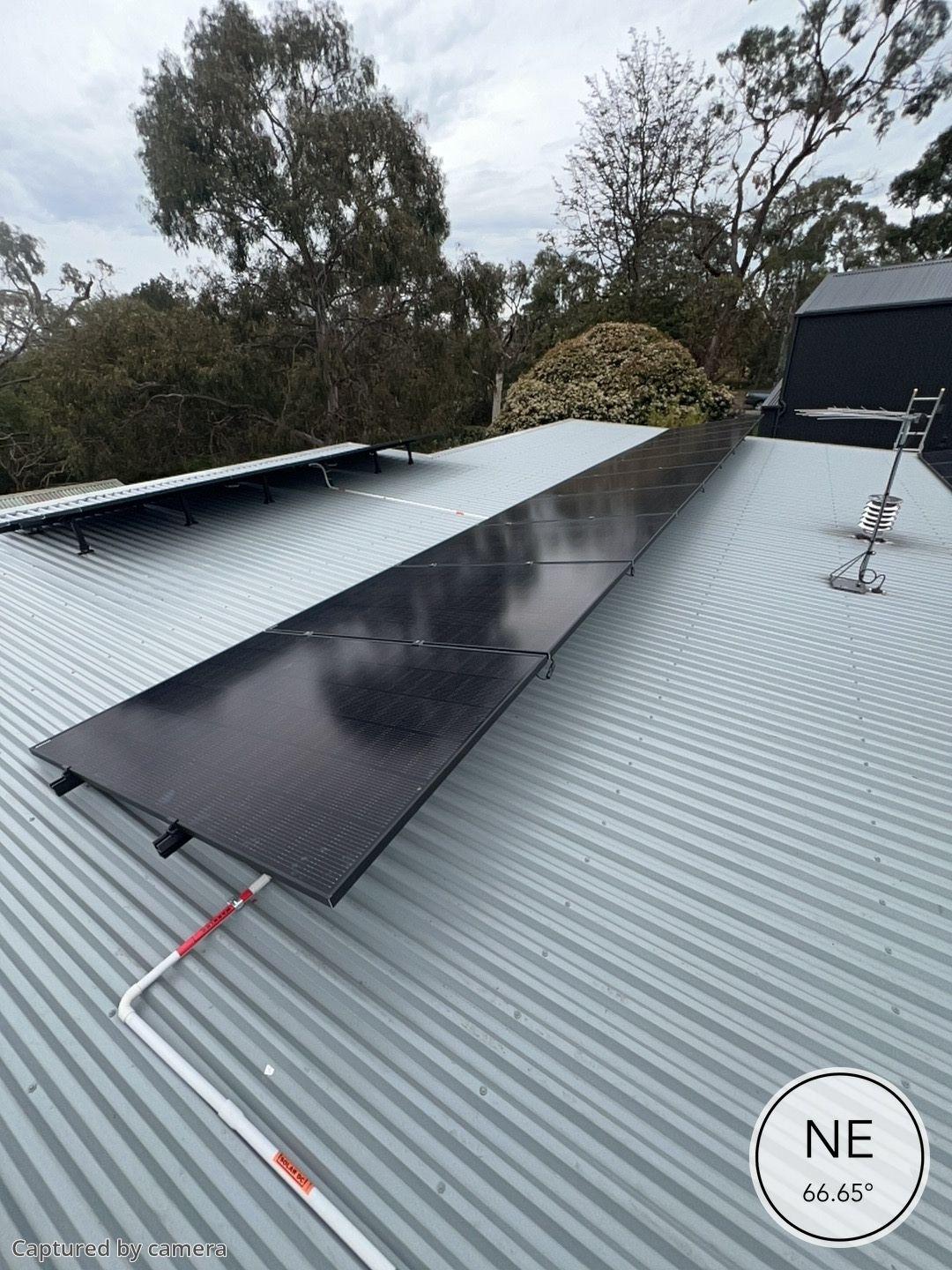 Thirty black solar panels on the tin roof of a cannons creek home, seen from above
