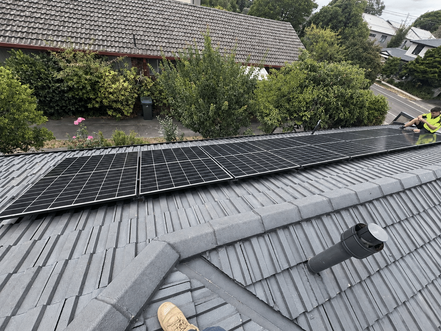 Fourteen jinko tiger neo panels in a single row on a tiled roof in doncaster, installer nearby