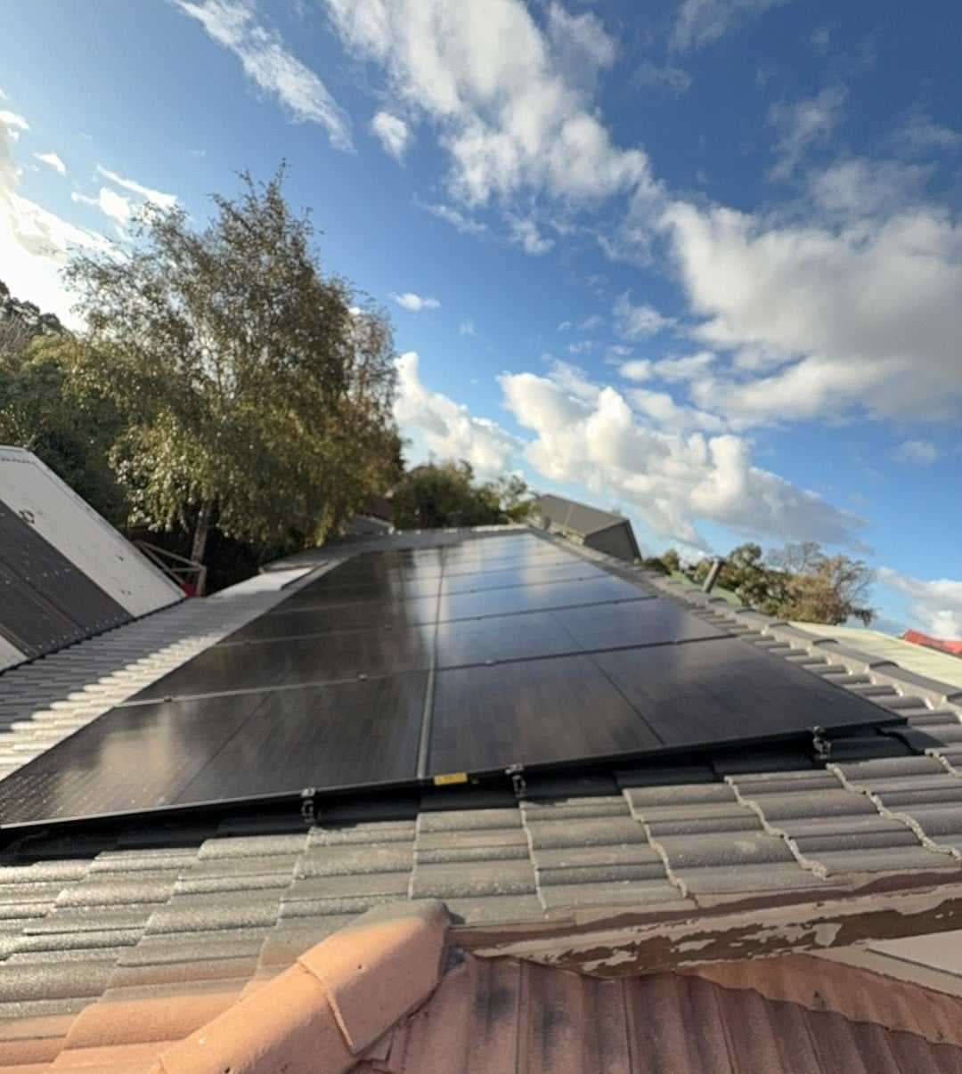 All-black jinko solar panels on a frankston south roof with trees behind, installed by powerband electrical