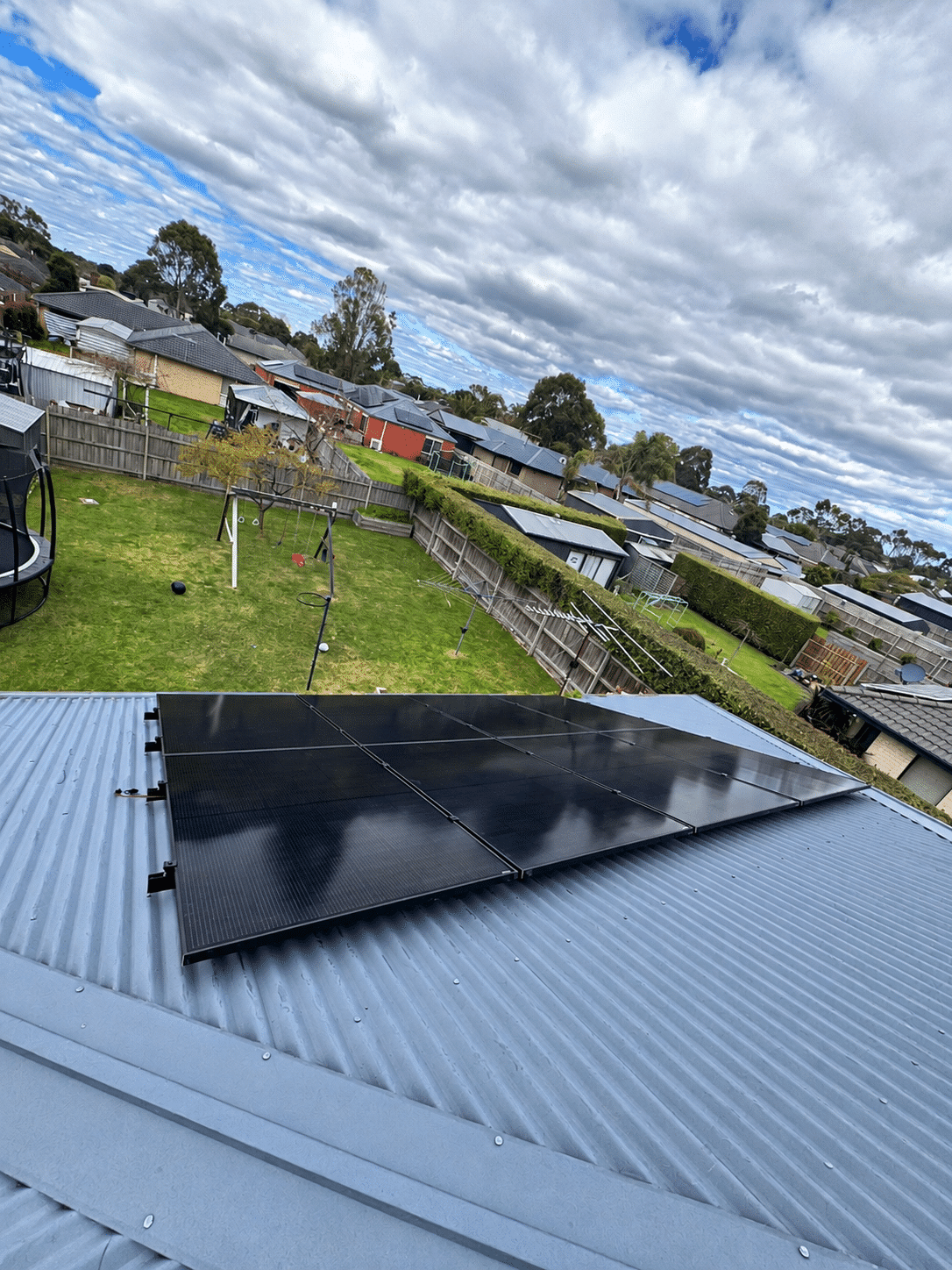 Solar panels along the tin roof of a hastings home, seen across the backyard