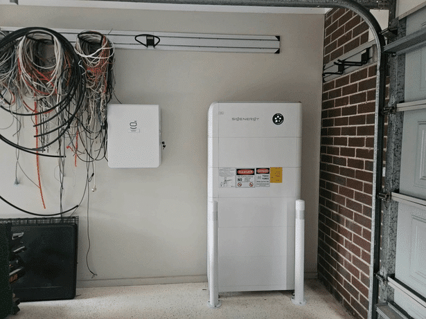 Sigenergy battery and gateway behind a bollard on a garage wall in lyndhurst