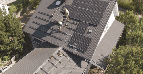 Aerial view of installers fitting solar panels on a mount martha roof